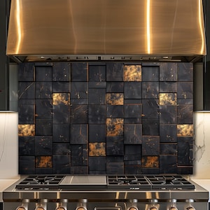 May include: A kitchen backsplash with a mosaic of dark, square tiles and gold highlights. The tiles are arranged in a grid, creating a textured surface. A stainless steel range hood is above the backsplash, and a gas range is below.