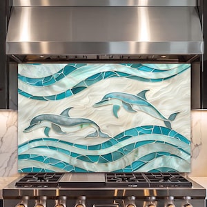 May include: A rectangular kitchen backsplash panel featuring a mosaic-style design of two dolphins swimming through stylized turquoise and teal waves against a swirling cream-colored background, installed behind a stainless steel gas stove.