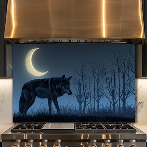 Puede incluir: Panel decorativo para cocina con una escena nocturna. La imagen muestra un lobo gris en silueta, una luna creciente brillante y árboles desnudos sobre un fondo azul oscuro. El lobo camina por hierba alta.