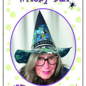 May include: A witchy hat with a black cone and a wide brim, featuring a blue and green floral design with the words "LA LUNA". The image includes the text "Witchy Hat" and a woman wearing the hat.