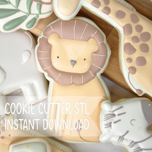 Peut inclure: Une collection de biscuits en forme d'animaux représentant un lion, une girafe et un zèbre avec des détails en glaçage blanc. Le texte COOKIE CUTTER STL INSTANT DOWNLOAD est superposé. Les biscuits sont décorés dans des tons neutres.