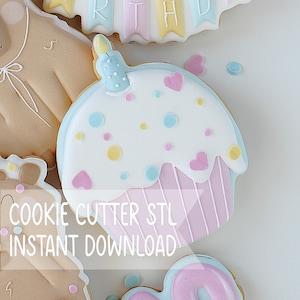 Puede incluir: Una galleta decorada con forma de cupcake con glaseado blanco, base de rayas rosa pastel, chispas de colores y una pequeña vela azul encima. El texto COOKIE CUTTER STL INSTANT DOWNLOAD está superpuesto. Se ven otras galletas parcialmente.