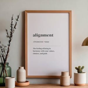 Könnte beinhalten: Ein gerahmter Druck mit dem Wort "alignment" und seiner Definition in schwarzem Text. Der Druck wird mit dekorativen Vasen, einem kleinen Topf-Kaktus und einer Pendelleuchte aus Messing ausgestellt.