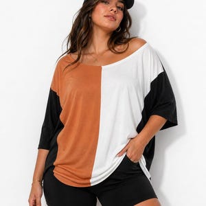 Pu&ograve; includere: Top a blocchi di colore con un design diviso in ruggine, bianco e nero. Il top ha maniche corte e una scollatura ampia. Abbinato a pantaloncini neri e un berretto da baseball nero.