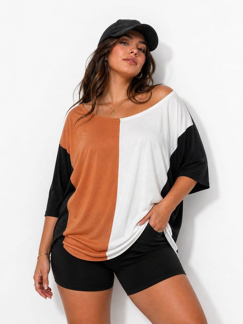 Pu&ograve; includere: Top a blocchi di colore con un design diviso in ruggine, bianco e nero. Il top ha maniche corte e una scollatura ampia. Abbinato a pantaloncini neri e un berretto da baseball nero.