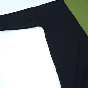 Pu&ograve; includere: Un top a maniche lunghe con un design a blocchi di colore. Il top presenta una manica e un pannello del corpo neri, contrastati da un pannello verde oliva. L'indumento &egrave; realizzato in un materiale morbido, probabilmente a maglia.