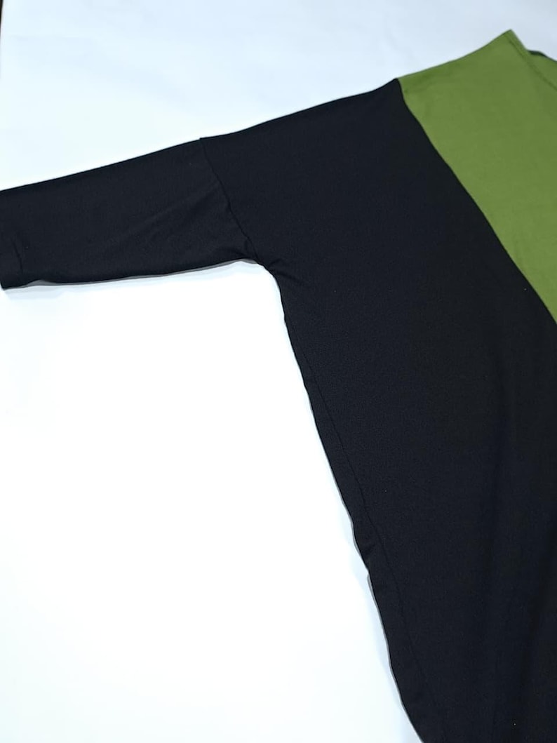 Pu&ograve; includere: Un top a maniche lunghe con un design a blocchi di colore. Il top presenta una manica e un pannello del corpo neri, contrastati da un pannello verde oliva. L'indumento &egrave; realizzato in un materiale morbido, probabilmente a maglia.