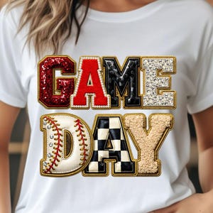May include: White t-shirt with the words "GAME DAY" in a decorative font. The word "GAME" is in red glitter, black, and silver glitter. The word "DAY" features a baseball and a black and white checkered pattern.