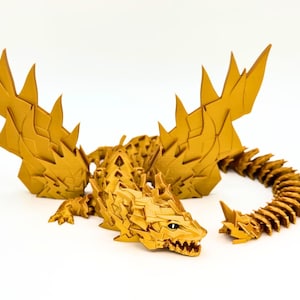 May include: A golden dragon figurine with detailed scales, sharp spikes, and articulated wings and tail. The dragon is posed on a white surface, showcasing its intricate design and craftsmanship. The dragon's mouth is open, revealing sharp teeth.