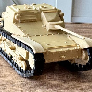 Könnte beinhalten: Ein beigefarbenes Modell eines Panzers mit schwarzen Ketten und einem Geschützrohr. Das Miniaturfahrzeug hat ein detailliertes Design, einschließlich Nieten und Luken. Der Panzer ist eine Nachbildung eines Militärfahrzeugs.