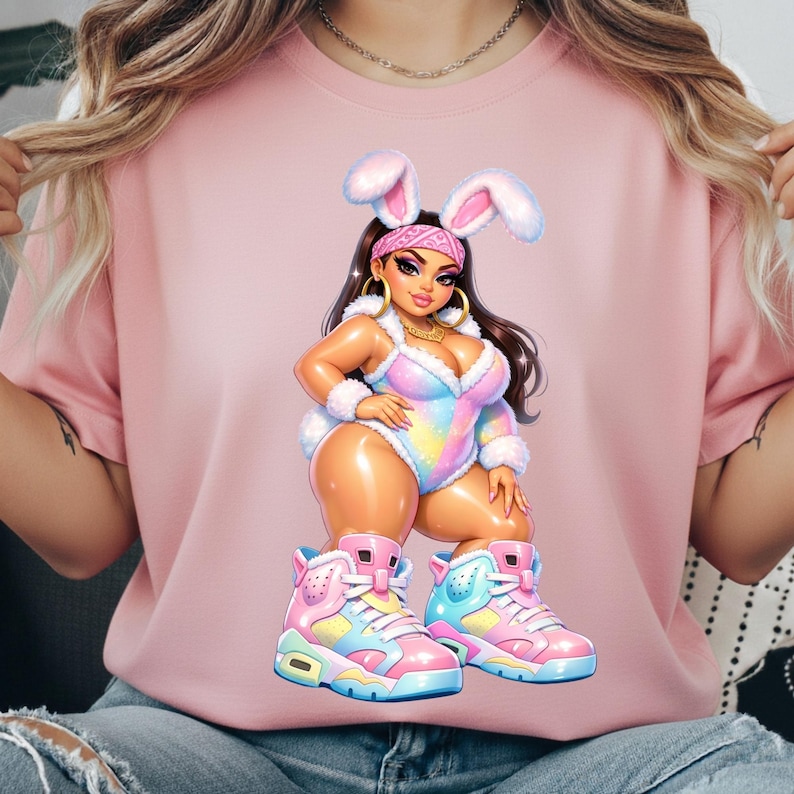 Puede incluir: Una camiseta rosa claro con una ilustraci&oacute;n gr&aacute;fica de un personaje con orejas de conejo, un body de arco&iacute;ris pastel con ribete de piel blanca y zapatillas altas. El personaje tiene el pelo largo y oscuro, pendientes de aro dorados y una bandana.