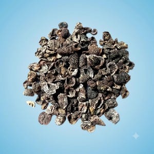 May include: A collection of dried, dark brown amla fruit pieces with a wrinkled, textured surface. The small, irregular fragments are clustered together, displaying various shades of deep brown and charcoal, showing a hollowed, organic structure.