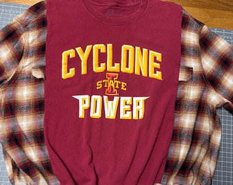 Een T-shirt van Iowa State Cyclone Power, hergebruikt met een tweedehands flanellen shirt en een trekkoord aan de onderkant.