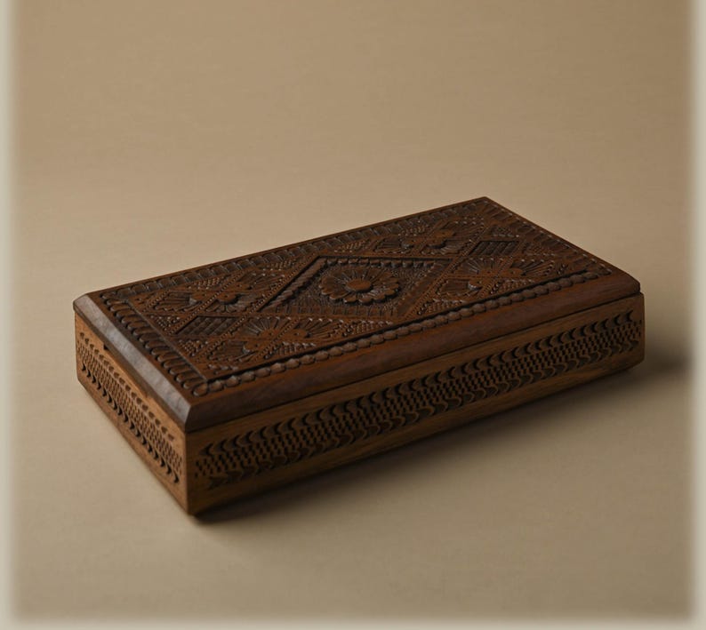 May include: A rectangular dark brown wooden box featuring intricate hand-carved geometric patterns and a central floral motif on the lid. The sides of the box are decorated with a repeating notched border design, showcasing detailed craftsmanship.