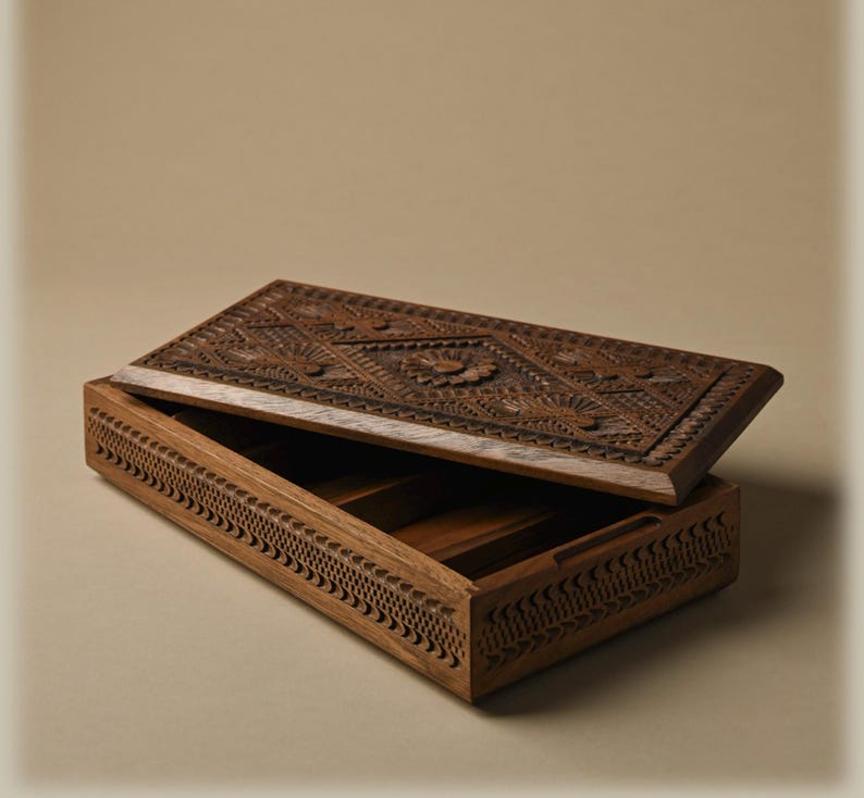May include: A rectangular wooden box with a partially open lid. The lid features intricate carved floral and geometric patterns. The sides of the box are decorated with a repeating notched border design. The interior is divided into three sections.