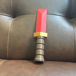 May include: A red and brown plastic toy sword with a textured handle.