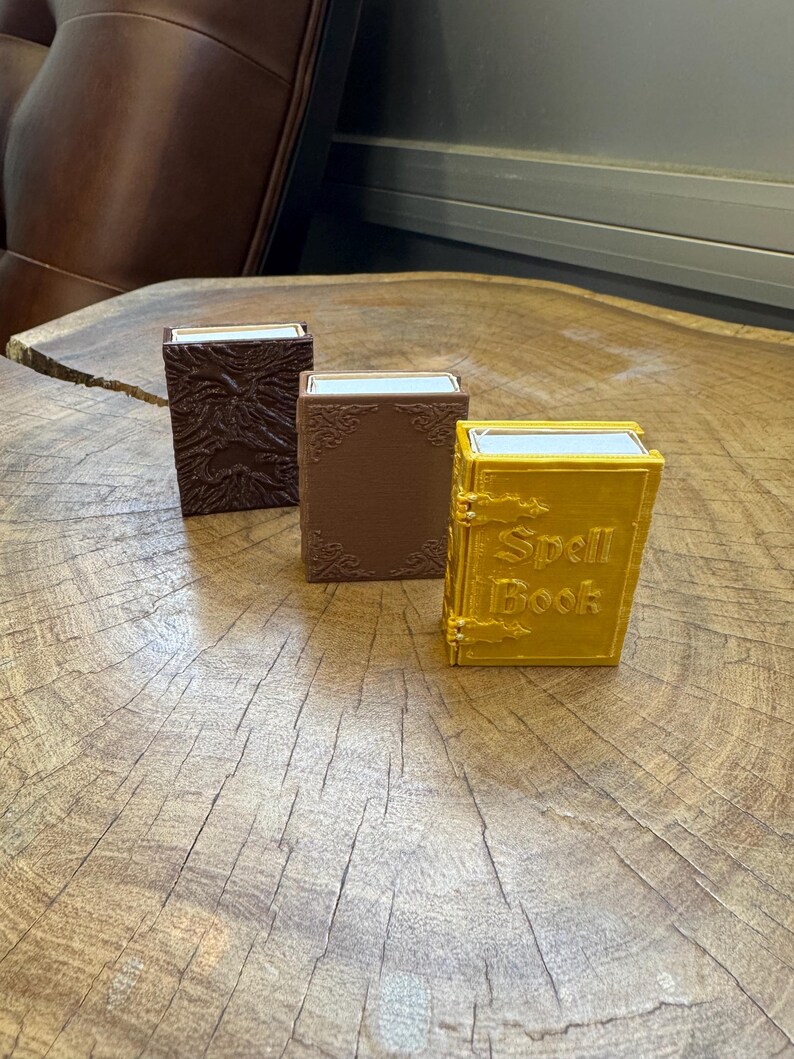 May include: Three small decorative boxes with a wood grain texture. The boxes are brown, brown, and gold. The gold box has the words "Spell Book" printed on the front.