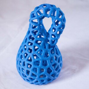 May include: A blue 3D printed vase with a lattice design. The vase has a unique shape with a loop at the top.