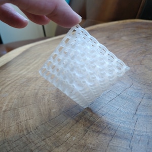 Puede incluir: Una l&aacute;mina de malla de pl&aacute;stico blanco con forma cuadrada y un patr&oacute;n tejido.