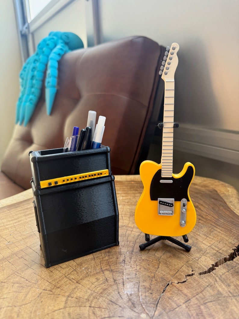 May include: A black and yellow guitar amplifier pencil holder with a yellow electric guitar on a stand.