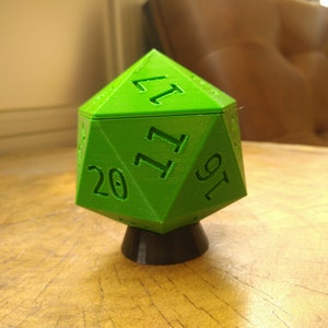 May include: A bright green 20-sided die with black numbers, resting on a black base. The die is a geometric shape with many sides and is a common tool used in tabletop role-playing games.