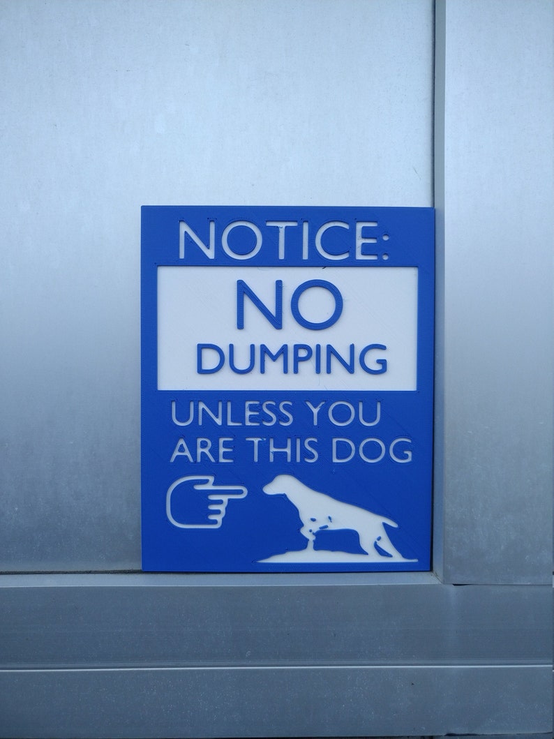May include: Blue sign with white text that reads "NOTICE: NO DUMPING UNLESS YOU ARE THIS DOG" with a white silhouette of a dog next to a pointing hand.