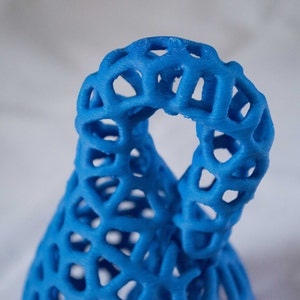 May include: A blue 3D printed sculpture with a lattice design. The sculpture is shaped like a vase or a bottle.