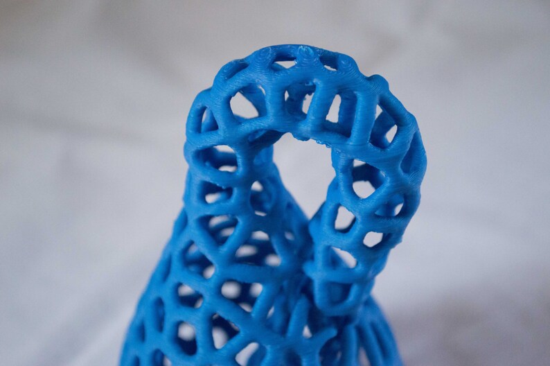 May include: A blue 3D printed sculpture with a lattice design. The sculpture is shaped like a vase or a bottle.