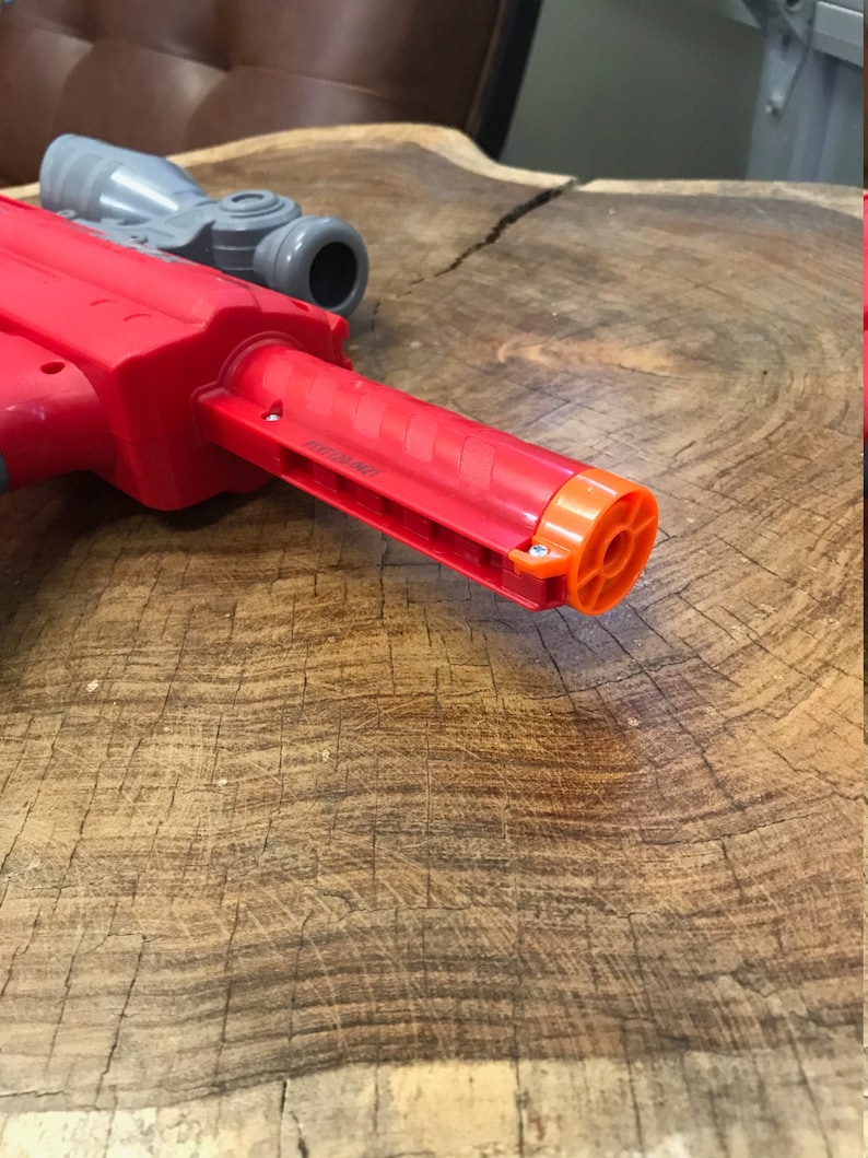 Peut inclure: Un jouet pistolet rouge avec une lunette grise et un canon orange. Le pistolet est en plastique et a une poign&eacute;e textur&eacute;e.