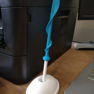 May include: A blue plastic sword with a white base. The sword is twisted and has a rounded tip. The base is a simple oval shape.