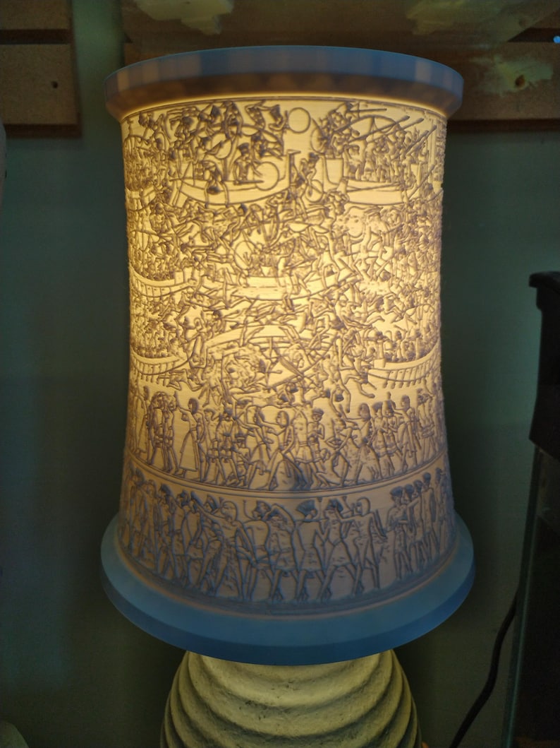 Pu&ograve; includere: Un paralume in ceramica bianca con un design intricato di persone e animali. Il paralume &egrave; illuminato dall'interno, proiettando una calda luce.