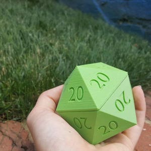 May include: A green twenty-sided die with the number 20 printed on each side.