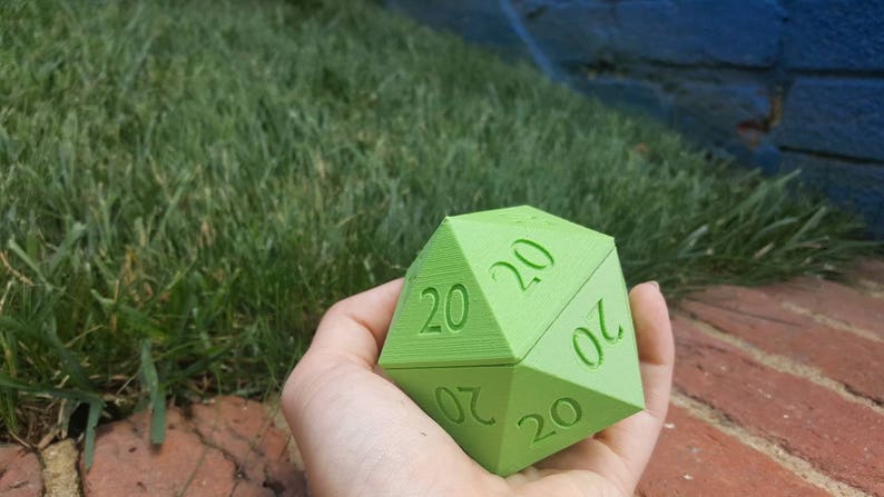 May include: A green twenty-sided die with the number 20 printed on each side.