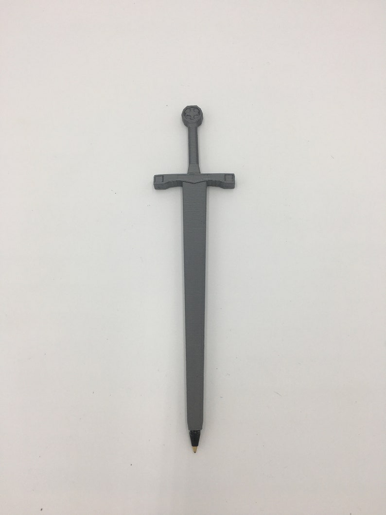 K&ouml;nnte beinhalten: Ein grauer Metallstift in Schwertform mit einem dekorativen Knauf. Der Stift ist etwa 15 cm lang.