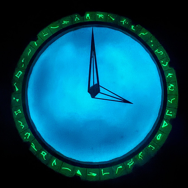May include: A clock with a blue face and green glowing symbols around the edge. The clock hands are black and point to the 12 o'clock position.