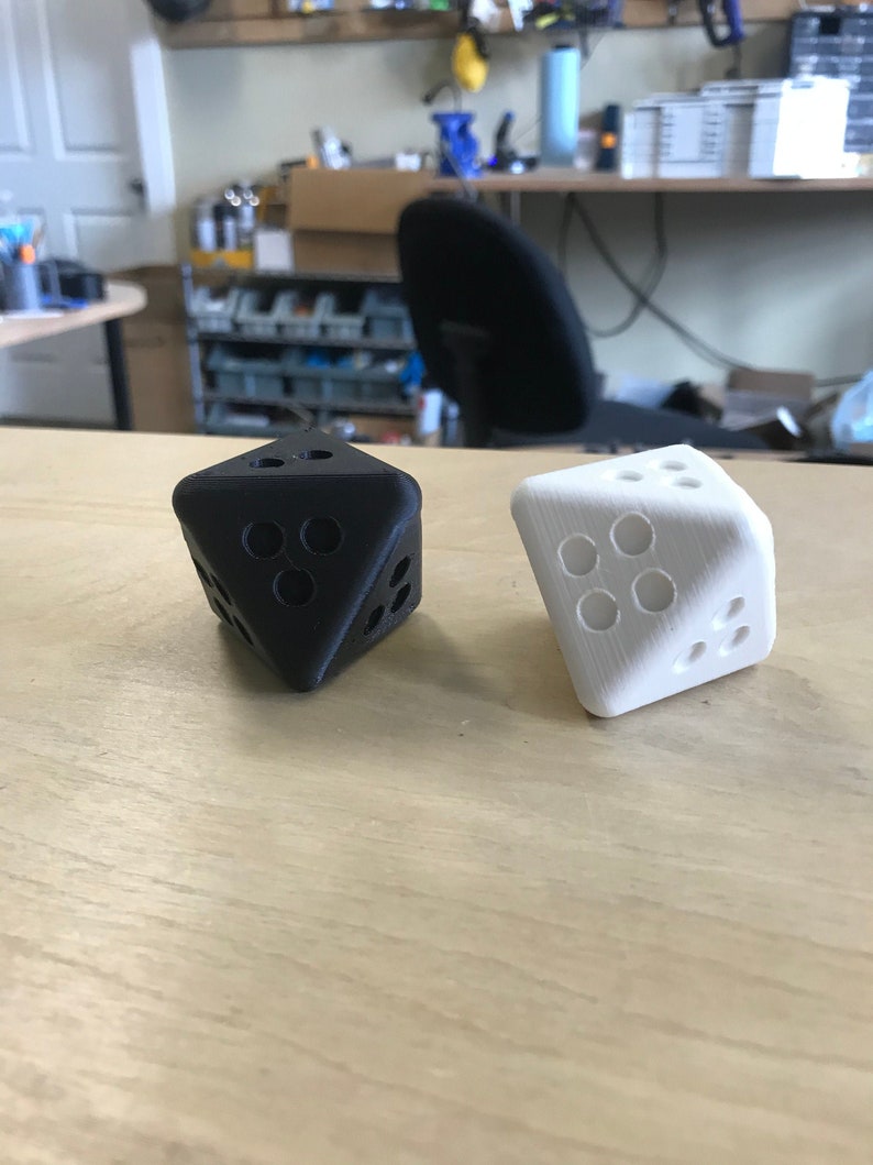 May include: Two dice, one black and one white, with a unique design. The dice are made of a smooth, hard plastic and have a slightly rounded shape.