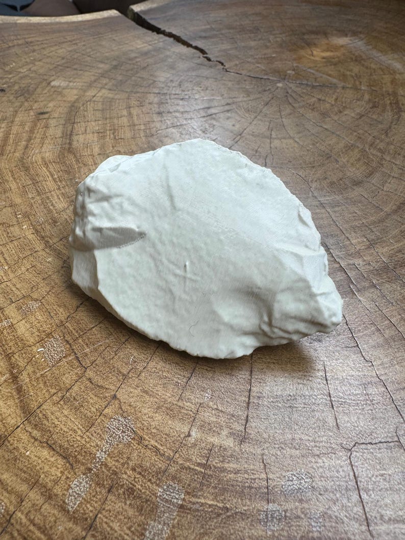 May include: A light gray, irregularly shaped stone with a rough, textured surface.