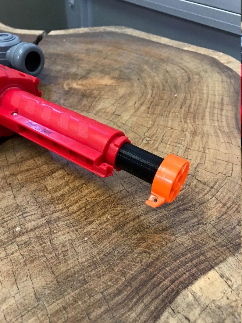 Peut inclure: Un jouet pistolet rouge et noir avec un embout orange. Le pistolet a une poign&eacute;e textur&eacute;e et un canon noir.