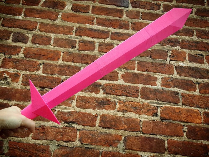 May include: A bright pink plastic sword with a pointed tip and a triangular handle.