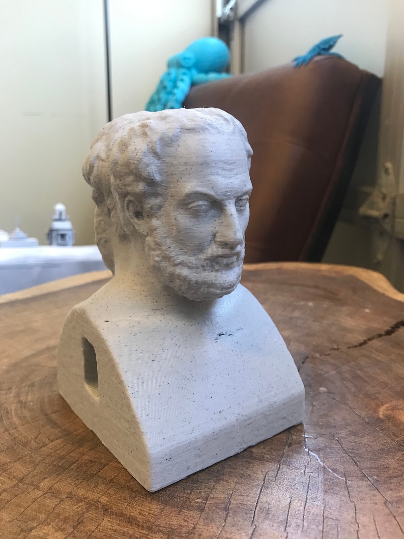 May include: A white plaster bust of a man with a beard. The bust is sitting on a wooden surface. The bust has a hole in the back.