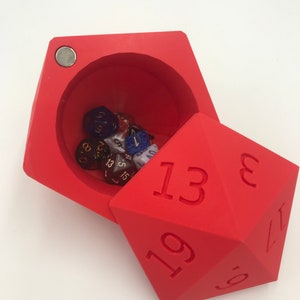 May include: Red dice tower with a lid that opens to reveal a compartment filled with various colored dice. The dice tower has the numbers 13, 19, 8, 17, and 5 printed on its sides.
