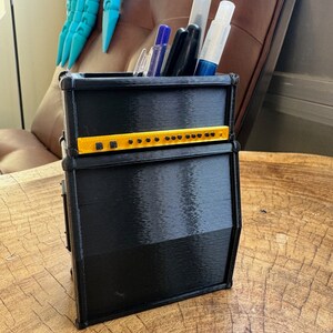 May include: Black and yellow guitar amplifier shaped desk organiser with pens and markers inside.
