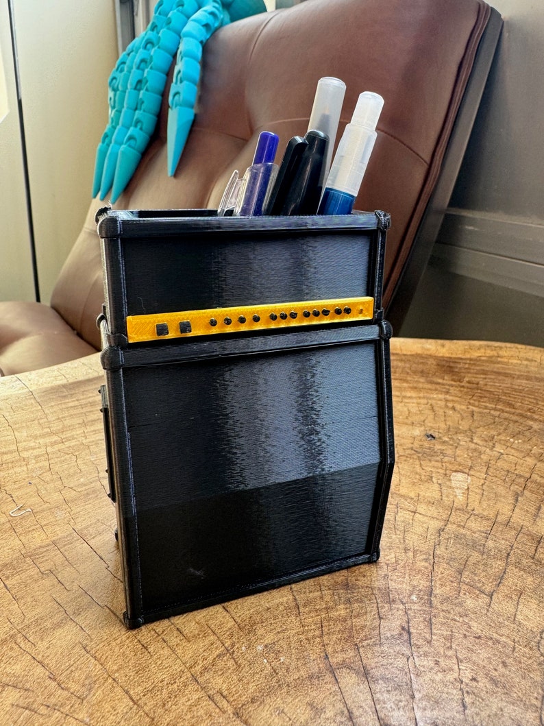 May include: Black and yellow guitar amplifier shaped desk organiser with pens and markers inside.