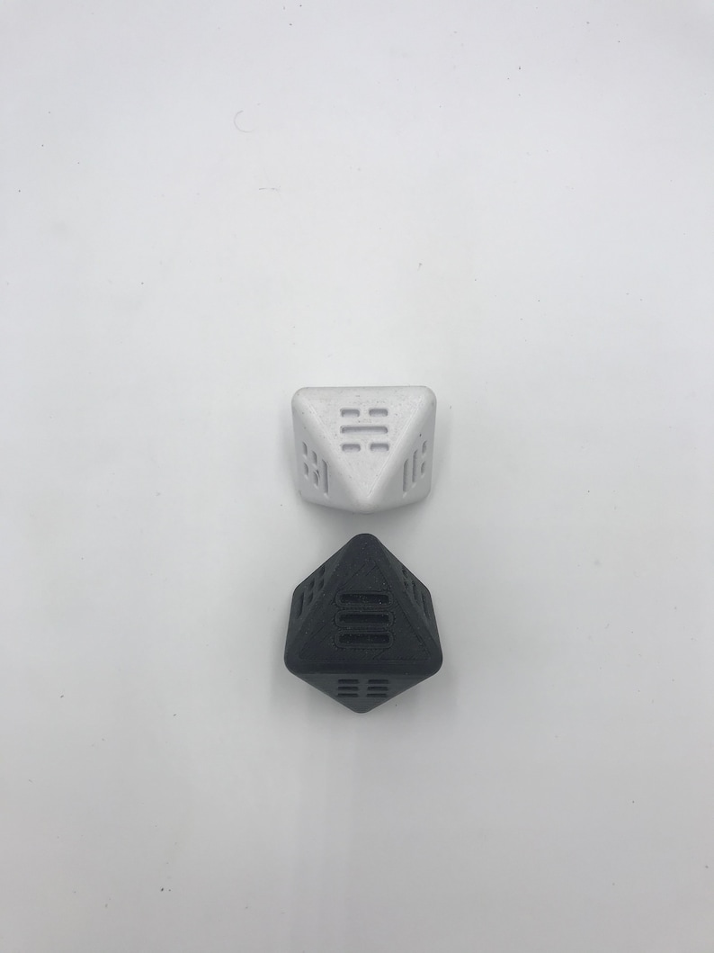 May include: Two geometric dice, one black and one white, with a unique design on each face. The dice are made of a textured material and are perfect for tabletop games.