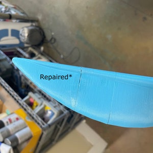 Puede incluir: Primer plano de un objeto de pl&aacute;stico azul claro, curvo, con una grieta reparada. El texto "Reparado*" est&aacute; escrito en el objeto.