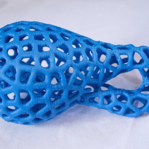 May include: A blue 3D printed object with a lattice design. The object is shaped like a long, thin oval with a hole in the middle.