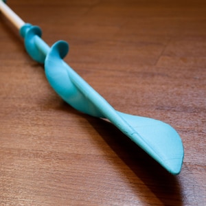 Puede incluir: Una herramienta de espiral de pl&aacute;stico azul y blanco con un mango de madera. La herramienta est&aacute; dise&ntilde;ada para perforar agujeros en el suelo.