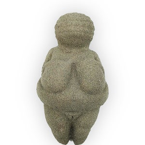 Puede incluir: Una peque&ntilde;a escultura de piedra gris que representa una figura femenina con rasgos exagerados. La escultura es lisa y tiene una superficie ligeramente texturizada.