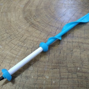 May include: A blue plastic pen with a white barrel and a spiral design. The pen is lying on a wooden surface.