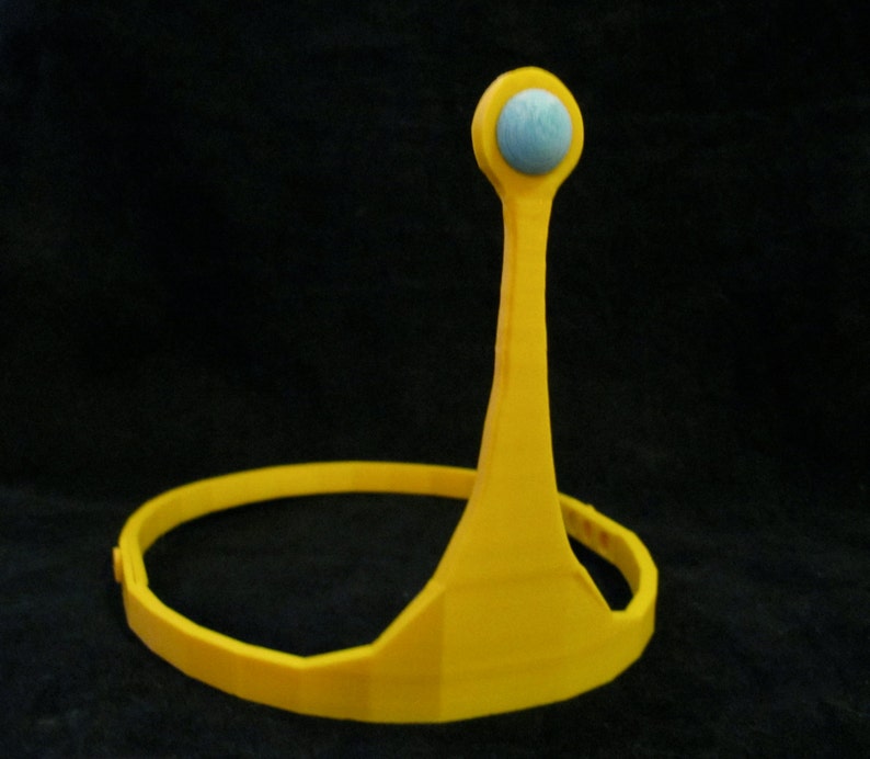May include: A yellow plastic crown with a blue jewel on top. The crown is designed to fit on a person's head.